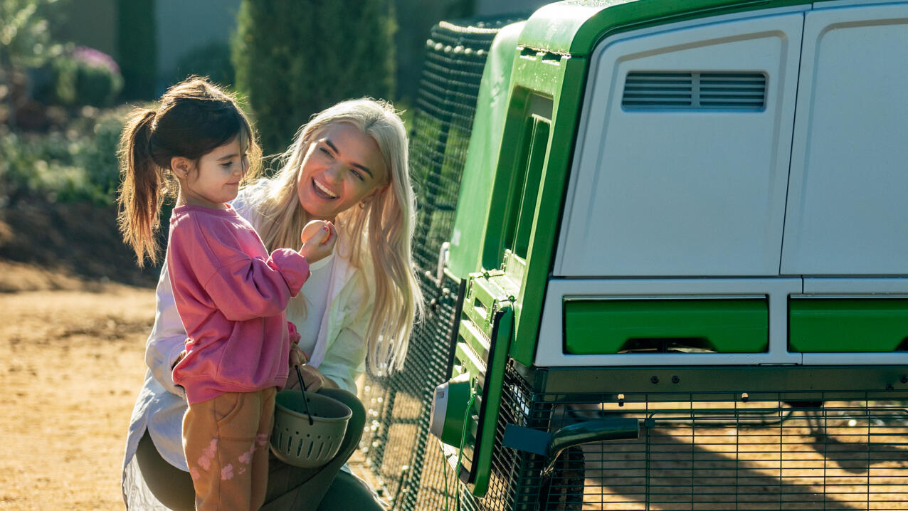 Mother and daughter collecting eggs from the Eglu pro chicken coop