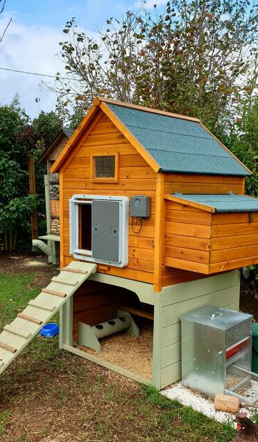 Omlet grey automatic chicken coop door attached to wooden chicken coop