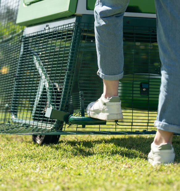 Foot releasing the wheel break to move the extra large Eglu pro chicken coop